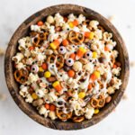 Bowl of Halloween monster munch party mix with popcorn, pretzels, candy corn and white chocolate coating